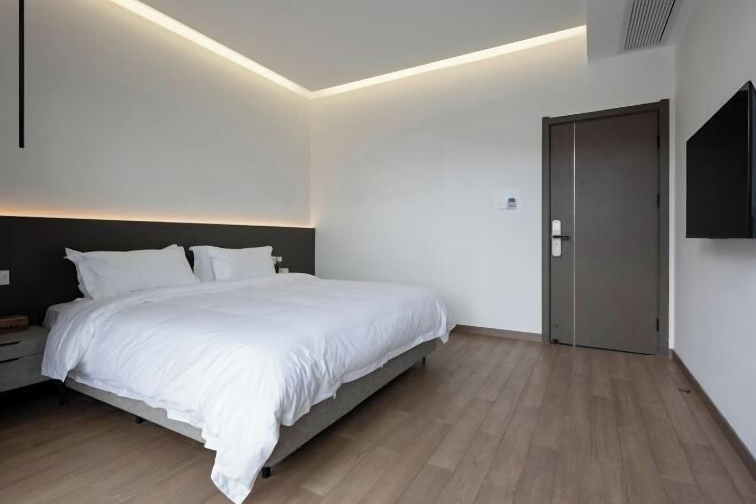 A modern bedroom with a bed, bedside table, and a door.