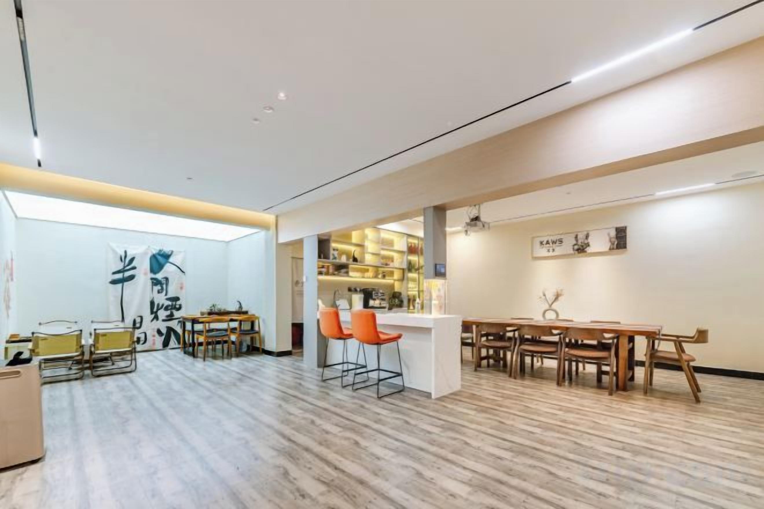Una habitación amplia con piso de madera, una zona de bar y un conjunto de asientos.