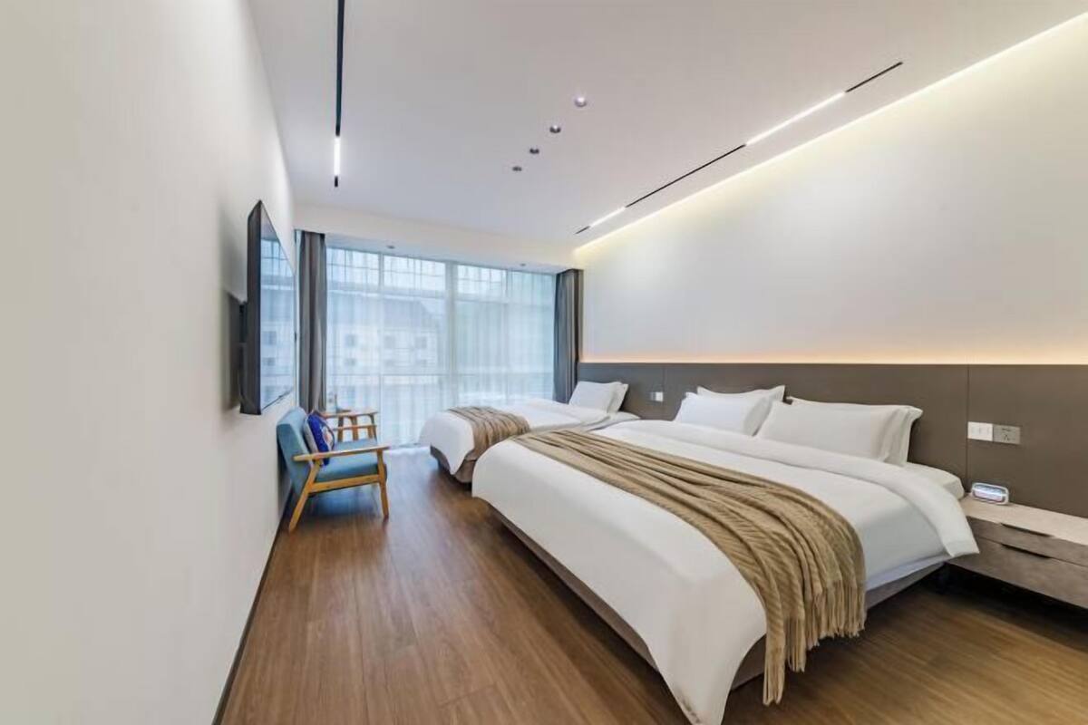 Ein modernes Hotelzimmer mit einem großen Bett, einem Nachttisch, einem Sessel und einem an der Wand befestigten Fernseher.