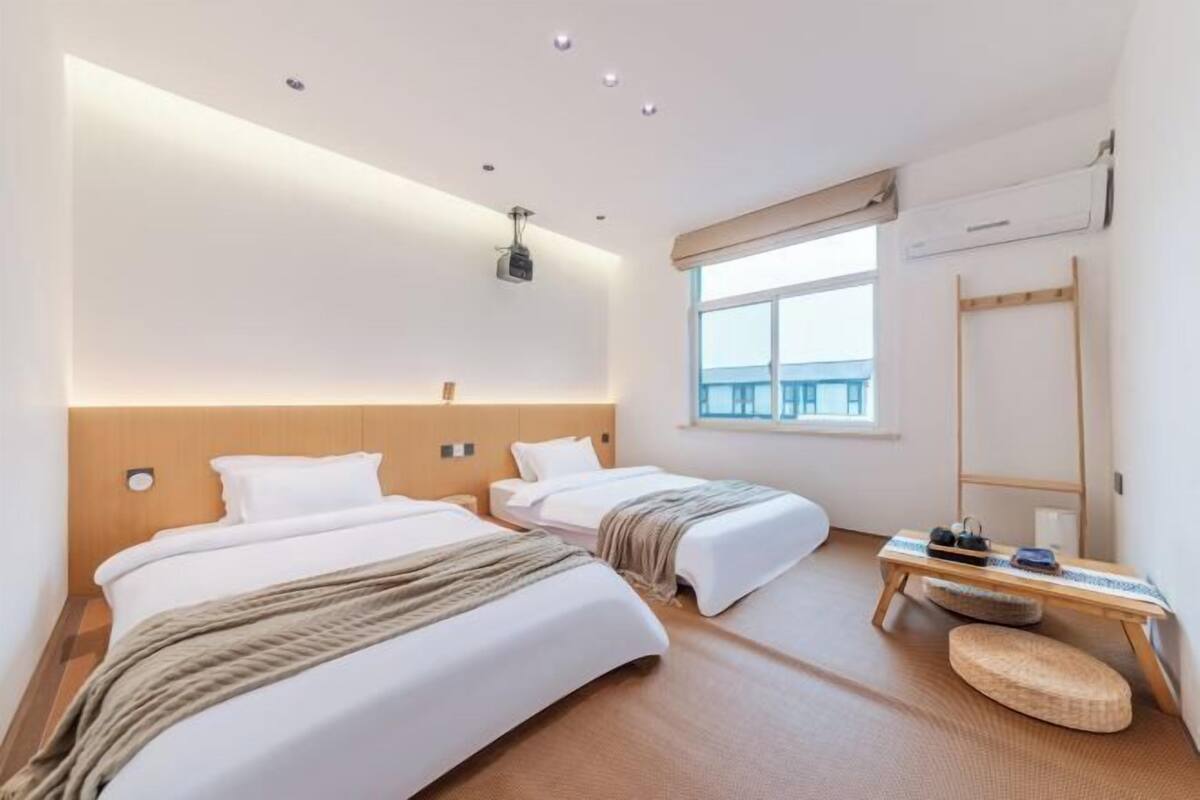 Ein Hotelzimmer mit zwei Betten, einem Nachttisch, einem Spiegel und einem Fenster mit Blick.