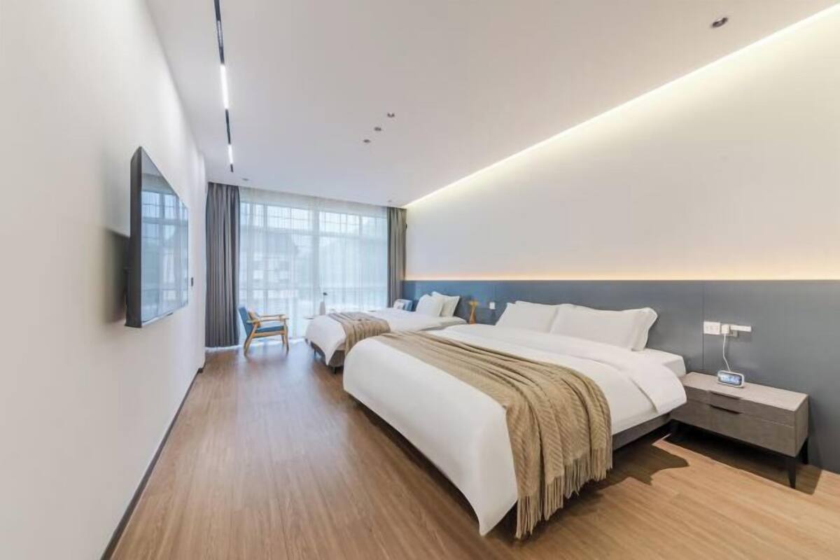 Ein modernes Hotelzimmer mit einem großen Bett, Nachttischen, einem Flachbildfernseher und Blick auf die Stadt.