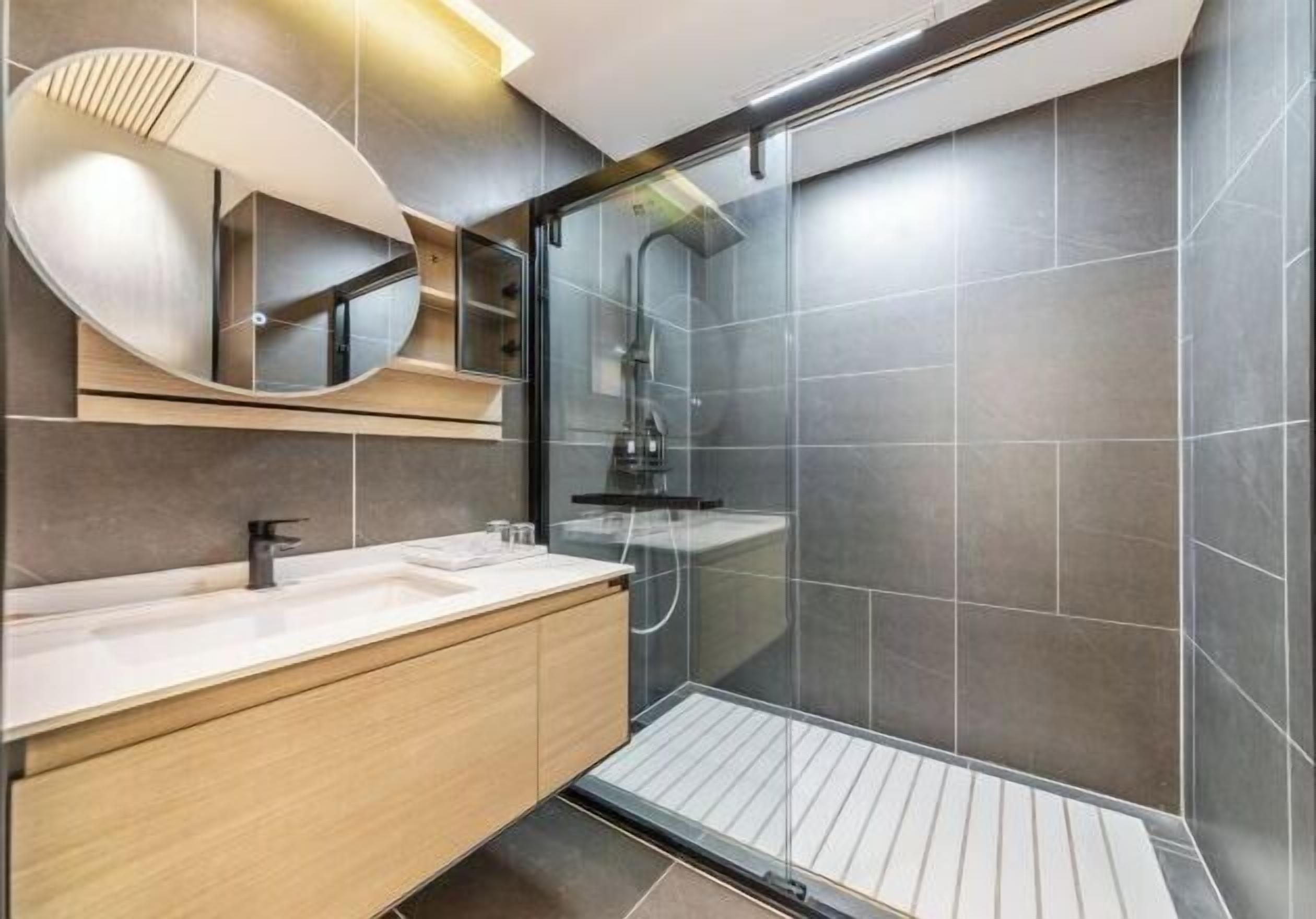 Ein modernes Badezimmer mit einem großen Spiegel, einer Dusche und einem Waschtisch.