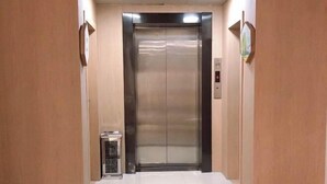An elevator in a hallway with a metallic finish and a control panel on the wall. - Yisu Qingju (Yuyao Shunbei Store) (Yuyao)