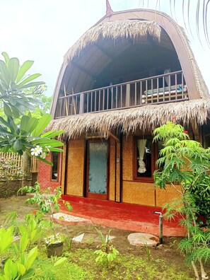 Une maison à deux étages, avec un toit de chaume et un balcon.