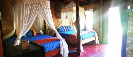 A room with two beds, each with a canopy, and a red floor.