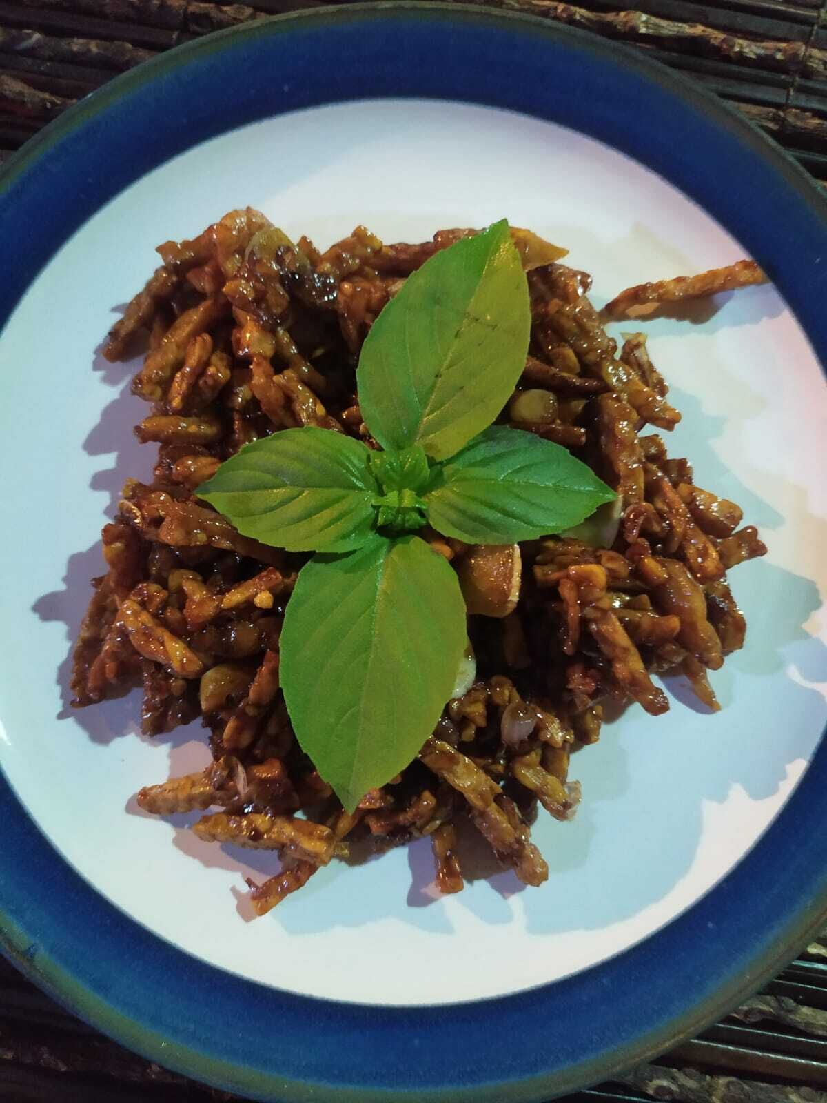 A plate of cooked food garnished with a green leaf, served on a blue and white plate.