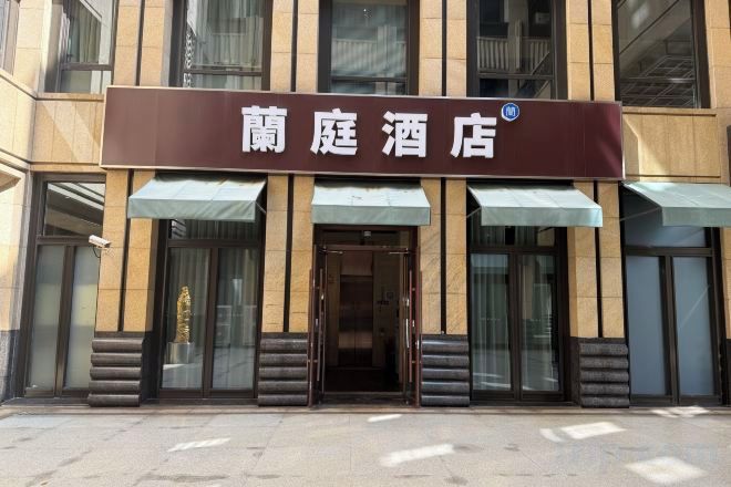 A hotel entrance with a sign that reads '蘭庭酒店' and a glass door.