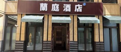 A hotel entrance with a sign that reads '蘭庭酒店' and a glass door.
