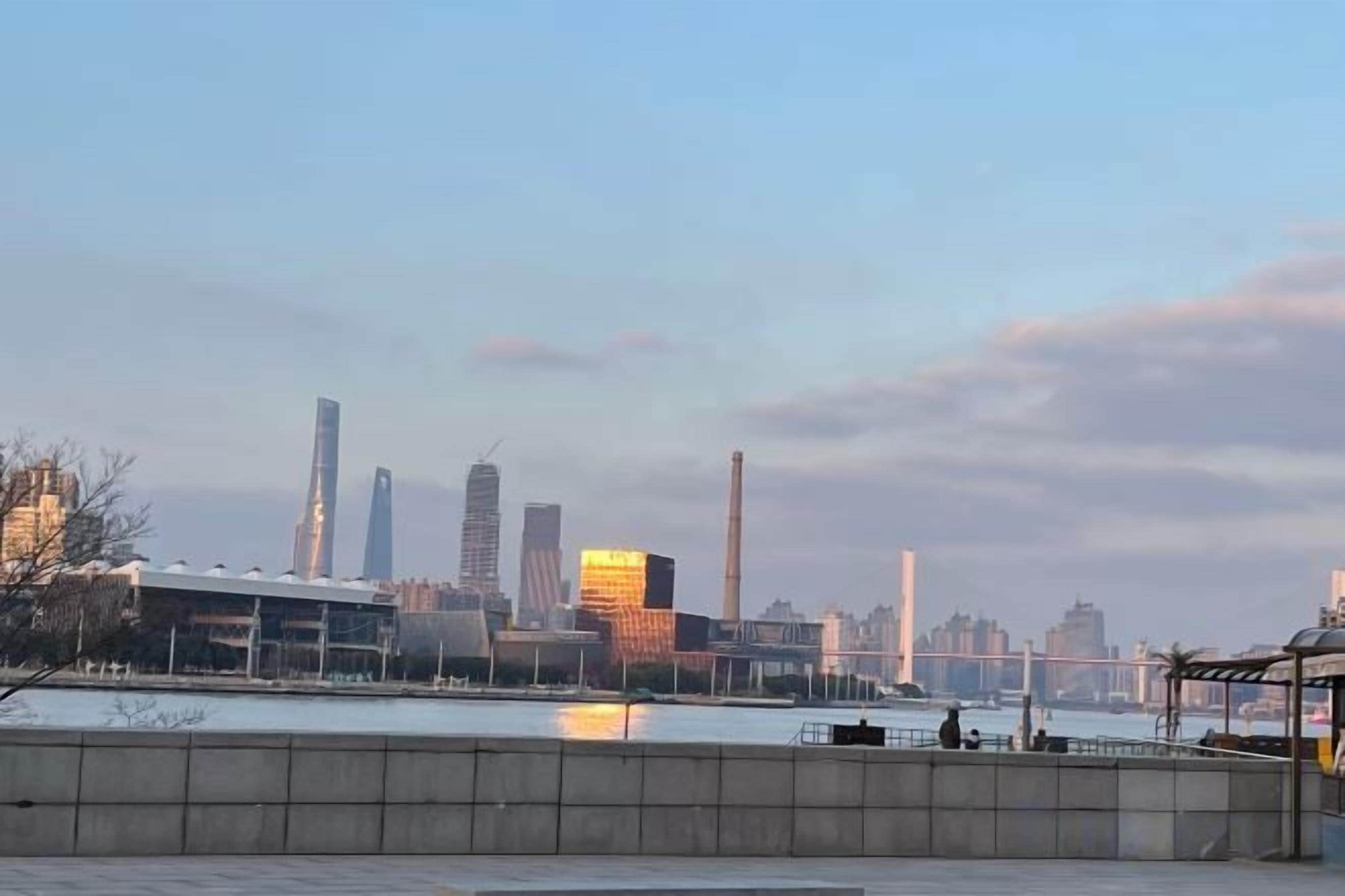 Une vue sur les grat-ciel d’une ville, avec des bâtiments modernes et une étendue d’eau au premier plan.