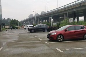 A parking area with cars and a bridge in the background. - Midor Hotel (Honggutan Wanda Plaza) (Nanchang)