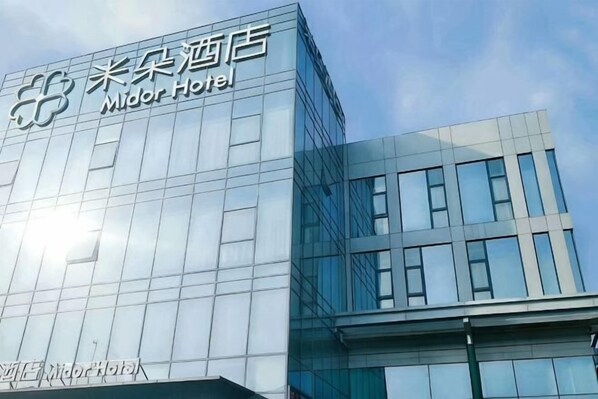A modern hotel building with a glass facade and a sign reading 'Midor Hotel.' - Midor Hotel (Honggutan Wanda Plaza) (Nanchang)