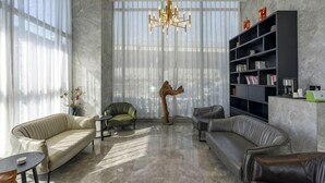 Un salon moderne comprenant un canapé, des fauteuils, une table basse, une bibliothèque et un lustre.