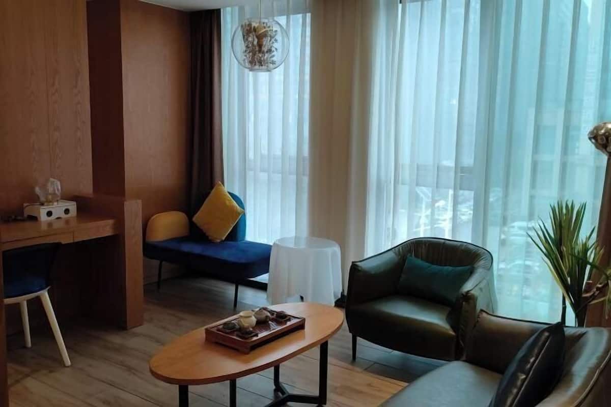 A modern living room with a wooden desk, a blue sofa, a leather armchair, and a round coffee table.