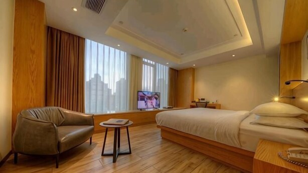 Une chambre d’hôtel avec un lit, un canapé, une petite table, une télévision et une vue sur la ville.