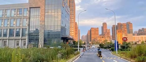 Una calle urbana con edificios modernos, cielo despejado y una vía con señal de prohibido el paso.