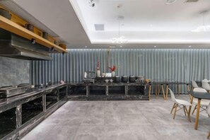 A modern kitchen with a central island, built-in appliances, and a dining area with chairs. - Midor Hotel (Honggutan Wanda Plaza) (Nanchang)