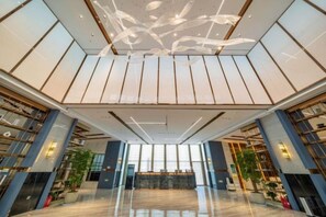 A spacious lobby with a high ceiling, large windows, and a central seating area. - Yearnsun Hotel (Taicang)