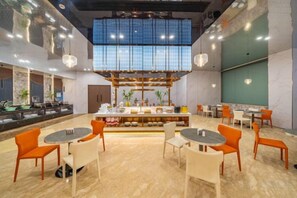 A modern hotel lobby with a central bar area, seating arrangements, and a large window providing natural light. - Yearnsun Hotel (Taicang)