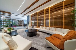 A modern interior with a sofa, coffee table, and a large window with a view. - Yearnsun Hotel (Taicang)