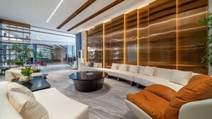 A modern lounge area with a sofa, armchairs, a coffee table, and a large window with a view of the outdoors. - Yearnsun Hotel (Taicang)