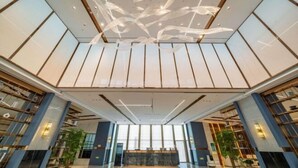 A spacious lobby with a high ceiling, large windows, and a central reception desk. - Yearnsun Hotel (Taicang)
