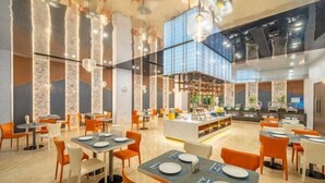 A modern restaurant with high ceilings, pendant lighting, and a central serving area. Tables are arranged around the space, and the floor is tiled. - Yearnsun Hotel (Taicang)