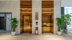 A lobby with marble flooring, two potted plants, and a reception desk. - Yearnsun Hotel (Taicang)