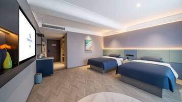 Habitación de hotel moderna con dos camas, un escritorio y zona de estar.