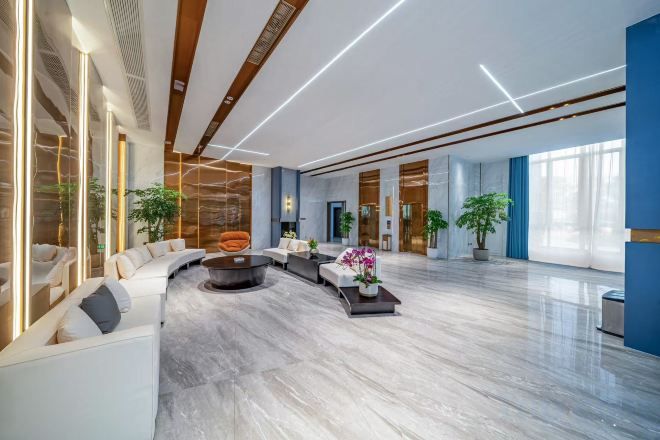 A spacious lobby with a curved seating area, a central coffee table, and large windows allowing natural light.