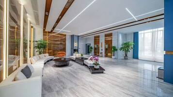 A spacious lobby with a curved seating area, a central coffee table, and large windows allowing natural light.