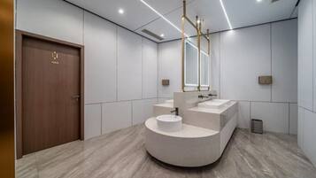 A modern bathroom with a wooden door, a curved vanity, and a large mirror.