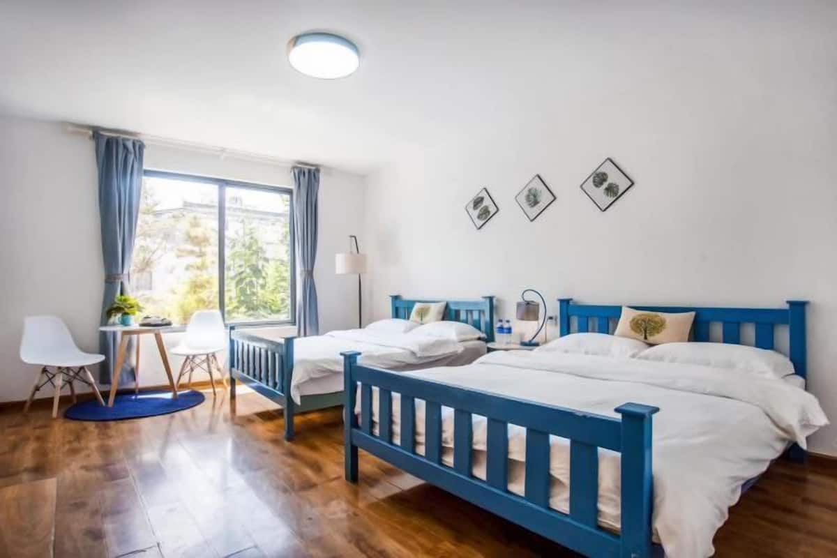 A bedroom with two beds, a desk, and a chair.