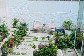 A patio with potted plants, a table, and two chairs. - FANMU GUESTHOUSE (Dali City)