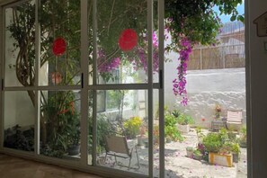 A room with a large window overlooking a garden with potted plants and a chair. - FANMU GUESTHOUSE (Dali City)