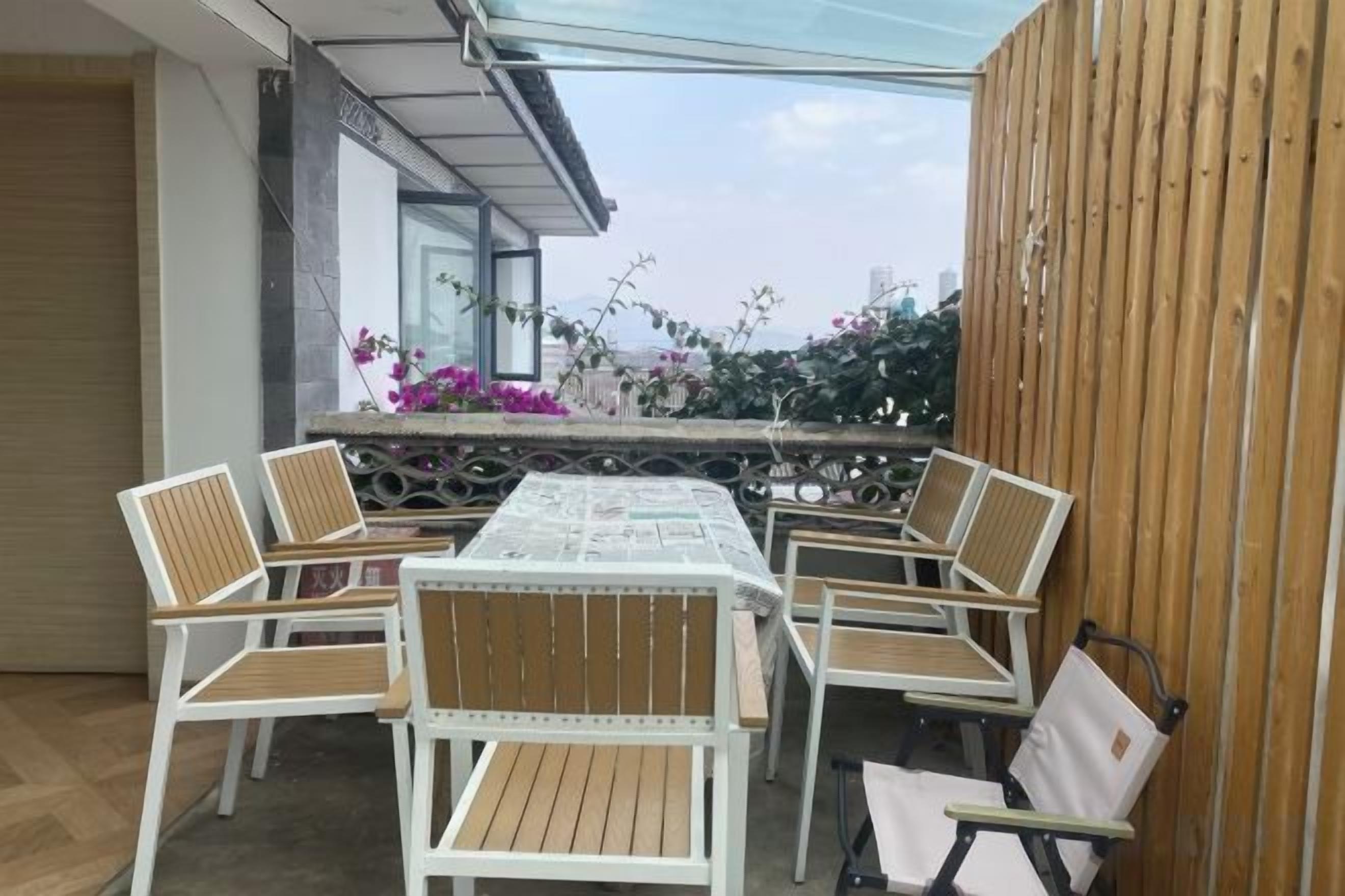 An outdoor patio with a table and chairs, a wooden fence, and a view of the city.