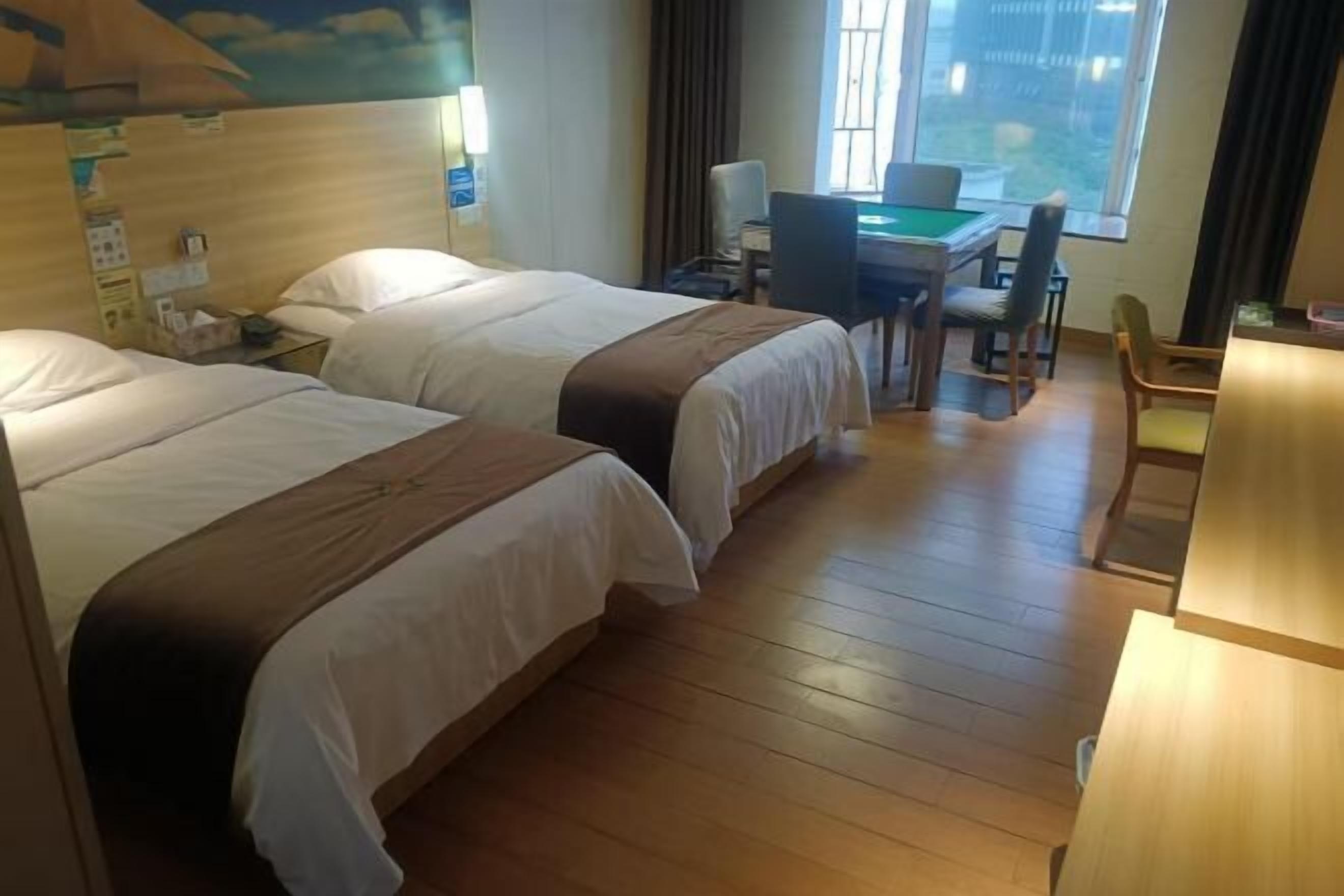 A hotel room with two beds, a desk with a chair, a pool table, and a view of the outdoors.