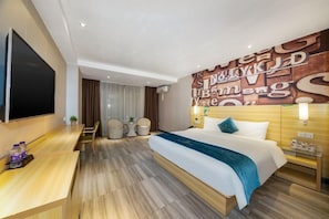 A hotel room with a bed, bedside table, lamp, and a wall with large letters.