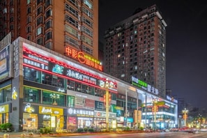 A multi-story commercial building with illuminated signage and storefronts.