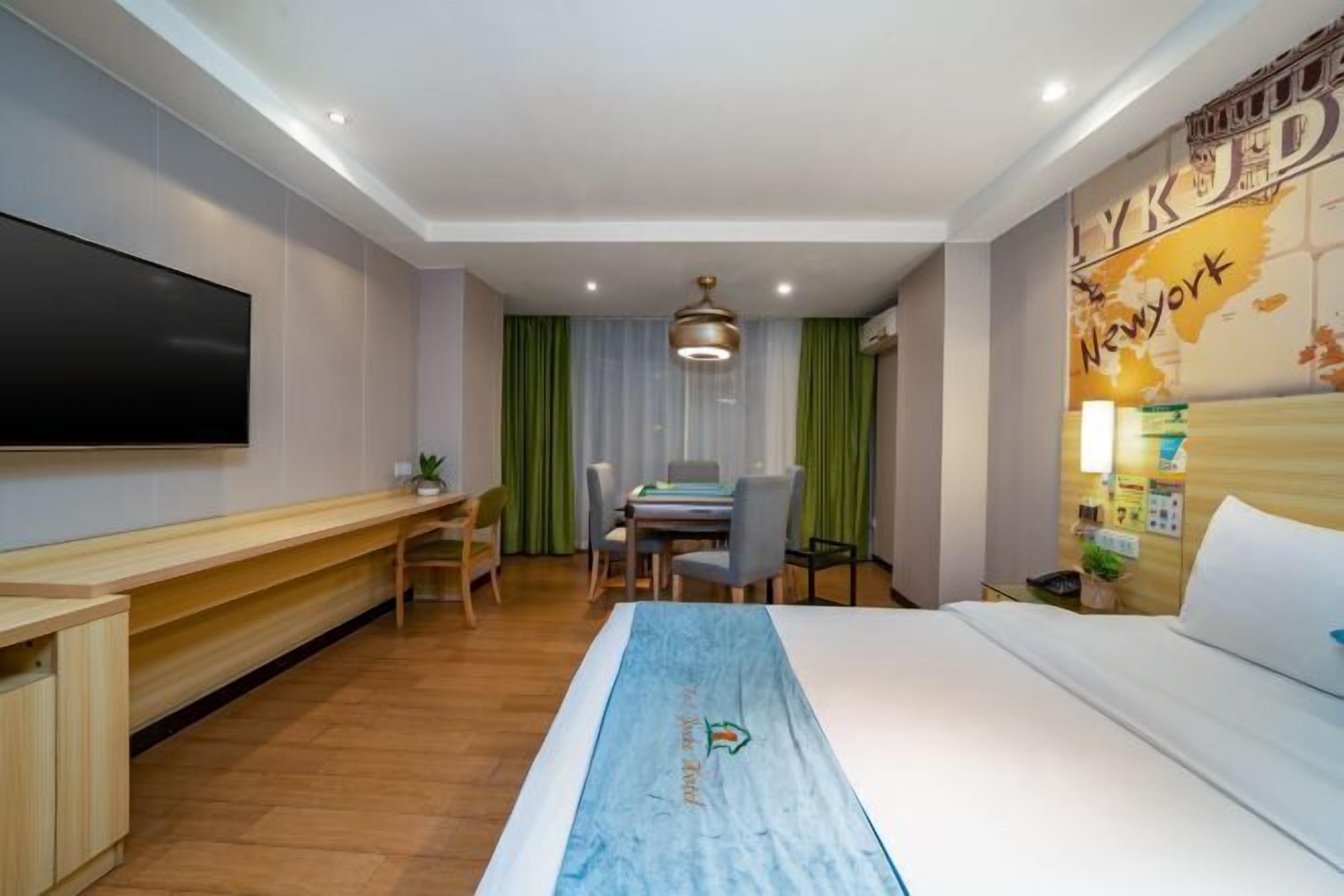 A hotel room with a bed, a desk, a chair, a TV, and a map on the wall.