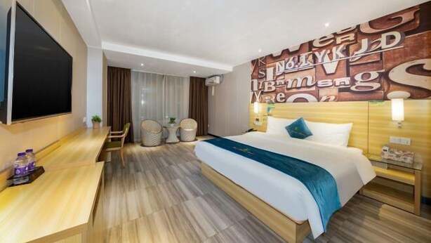 A modern hotel room with a large bed, a desk, and a wall with decorative letters. - NO.1 Youke Hotel(Dongguan Shebei store) (Dongguan)