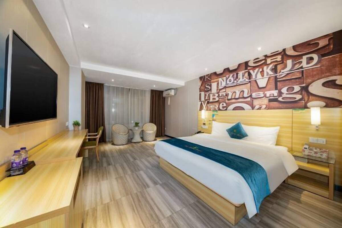 Une chambre d’hôtel moderne avec un grand lit, un bureau et un mur décoré de lettres.