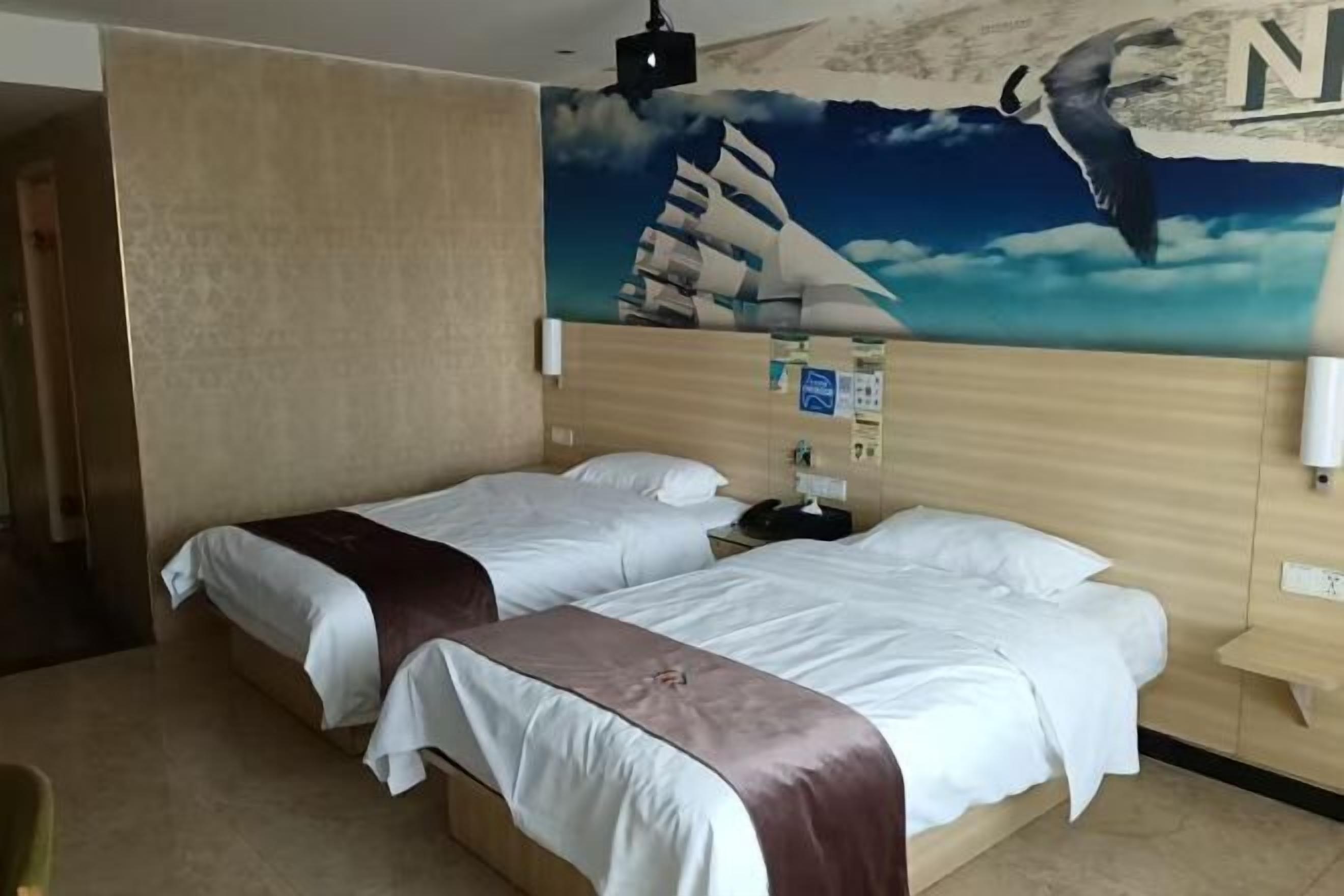 A hotel room with two beds, a mural of a sailboat and a bird, and a wooden headboard.