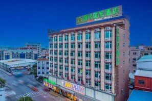 A multi-story hotel with a prominent green sign at the top.