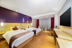 A hotel room with two beds, a desk, a TV, and a cityscape mural on the wall.