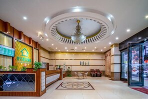 A hotel reception area with a modern design, including a reception desk, seating area, and a chandelier.