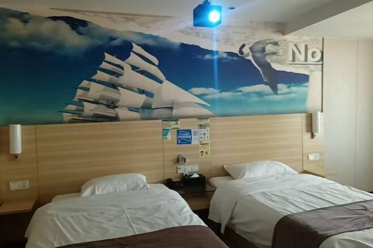 Une chambre d’hôtel avec deux lits, une tête de lit en bois, une carte murale et une lampe de chevet.