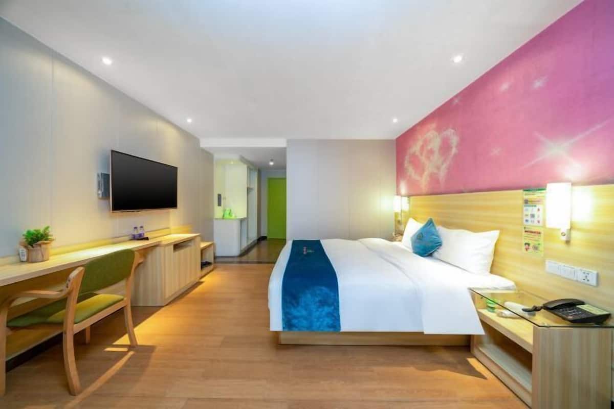 Une chambre d’hôtel comprenant un lit, une table de chevet, une lampe et un bureau avec une chaise.