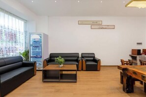 Un moderno vestíbulo de hotel con un sofá de cuero negro, una mesa de centro de madera y una máquina expendedora.