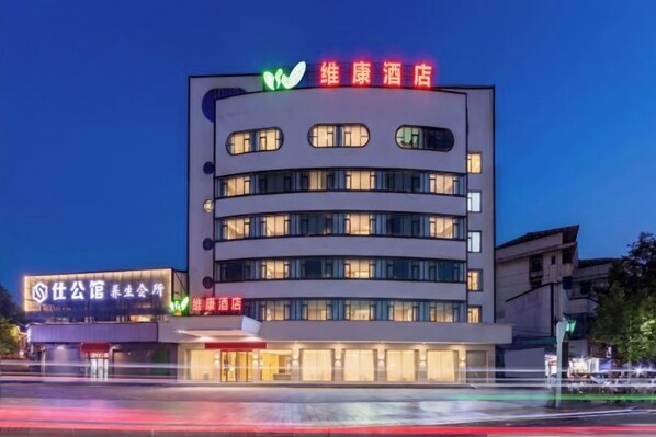 Un hotel de varios pisos con un diseño moderno, que destaca por un letrero prominente en la parte superior y una fachada bien iluminada.