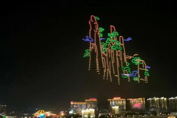 A nighttime cityscape with illuminated buildings and a decorative light display.